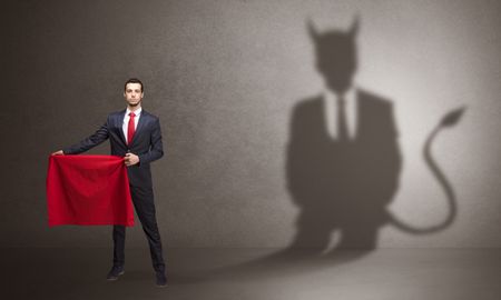 Businessman standing with red cloth in his hand and devil shadow on the background