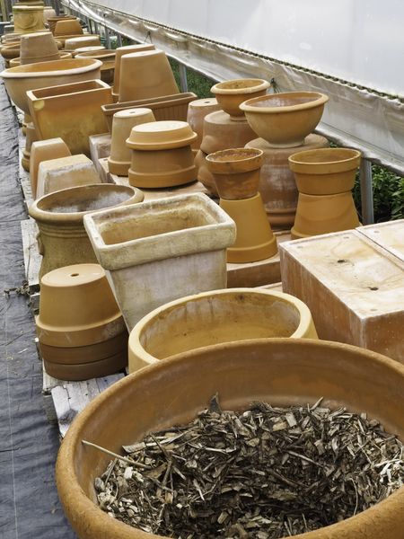 Assortment of terra cotta flowerpots and plant pots outside a greenhouse in springtime