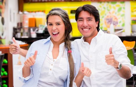 Positive couple with thumbs up looking happy