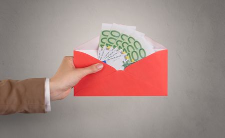 Female hand holding coloured and white envelope with empty wall background