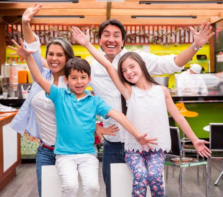 Excited family with arms up at a restaurant