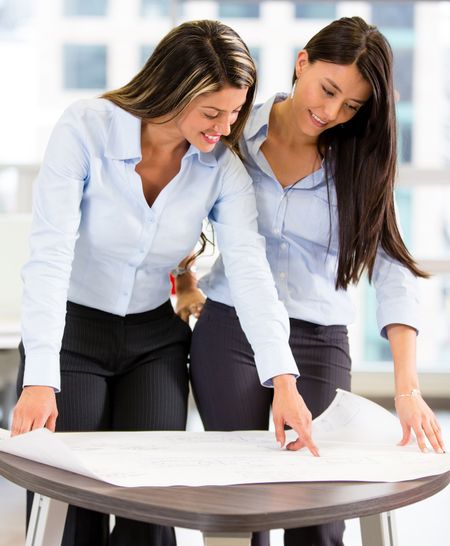 Business women looking at blueprints in the office