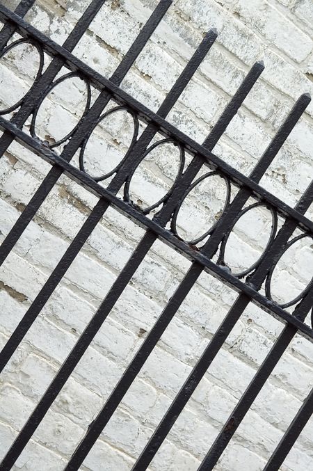 Wrought iron fence by weathered white wall