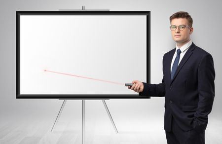 Young businessman with laser pointer and copyspace white wall