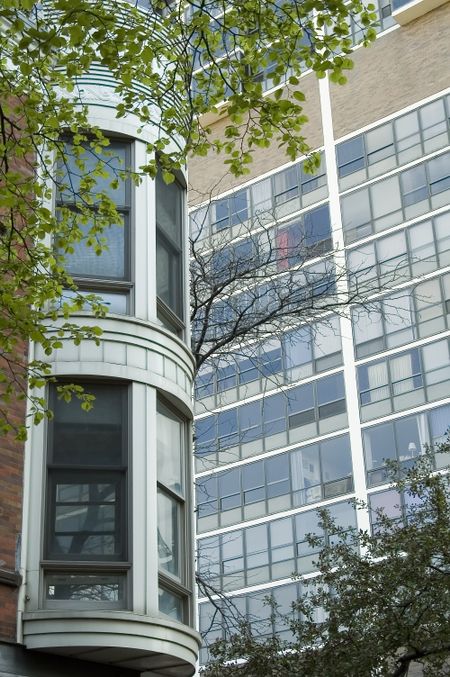 Corner of old building with bay windows across street from high-rise