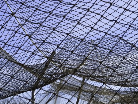 Complexities of practice: Part of netting over batting cage by baseball field on campus of community college