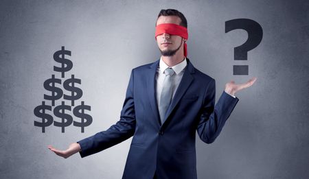 Serious businessmen standing in front of a grey wall with red ribbon on his eye, holding dollars