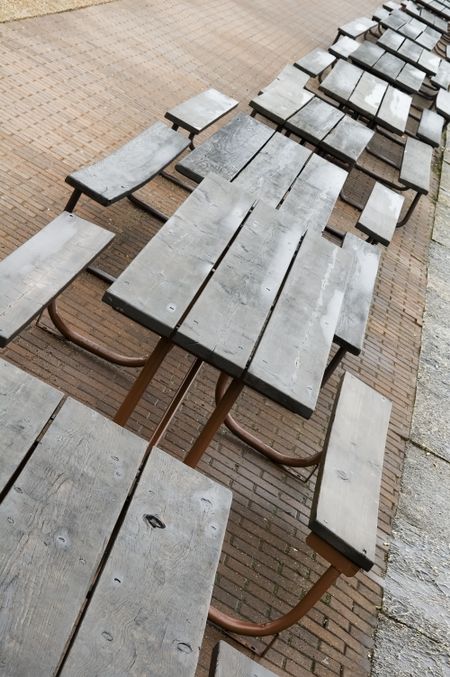 Row of wet picnic tables on pavement