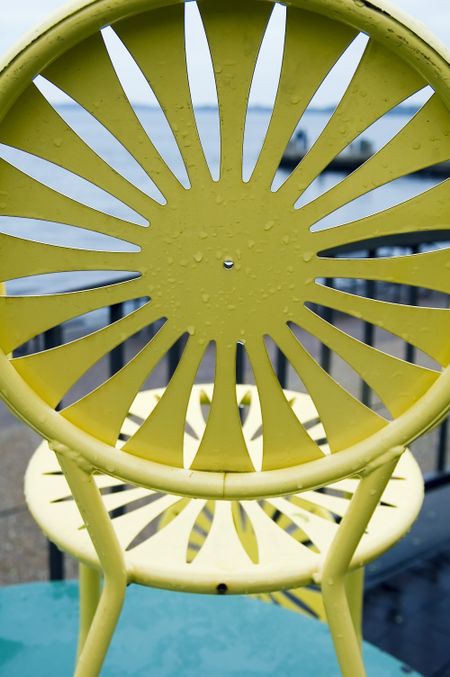 Yellow chair with sun motif overlooking lake on a rainy day