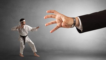 Small karate man fighting with big hand