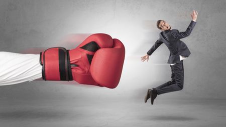 Businessman gets a hit from a giant hand with boxing gloves