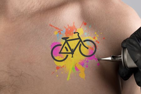 Hand tattooing colourful bicycle concept on naked clear skin