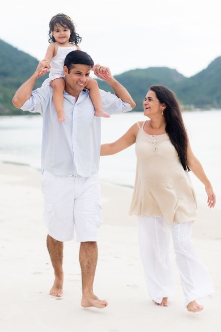 Happy family expecting a new child and walking at the beach