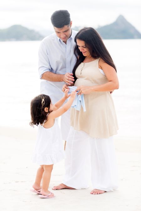 Girl excited about her coming sister placing clothes on pregnant belly