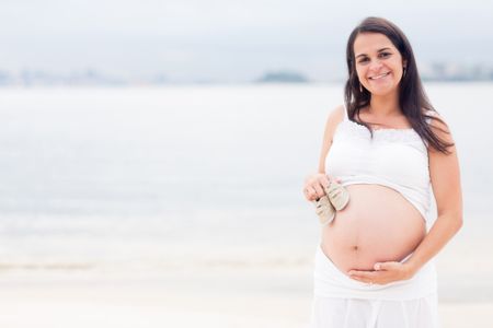 Beautiful pregnant woman at the beach looking happy