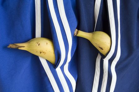 Two bananas peeping from pockets of blue and navy gym shorts