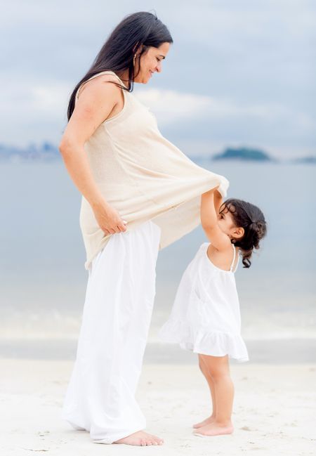 Pregnant mother and beautiful daughter looking to her belly