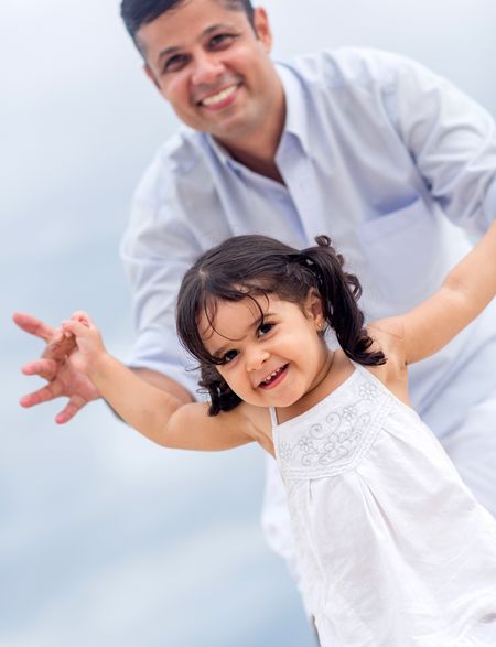Happy little girl playing with his father outdoors