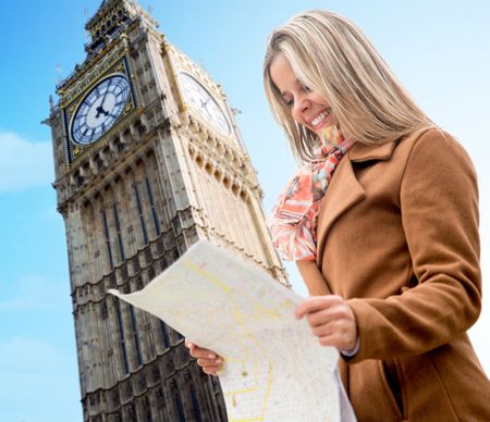 Happy woman sightseeing in London holding a map and smiling