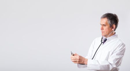 Middle aged doctor listening to empty copy space with stethoscope