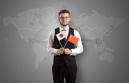 Cheerful businessman standing in front of a map with flag on his hand