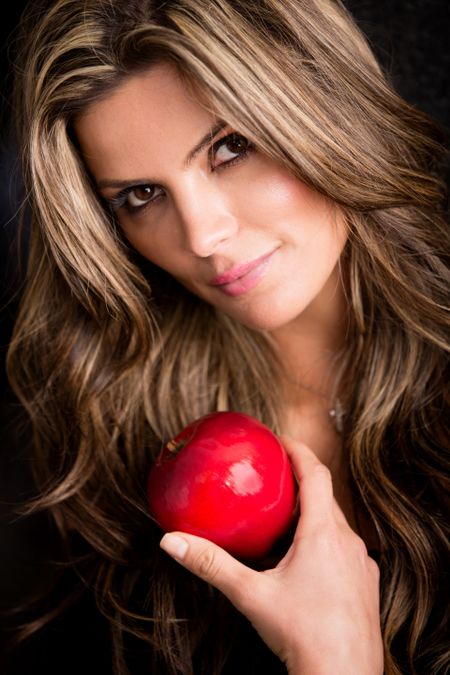 Beautiful woman portrait holding an apple - isolated over black