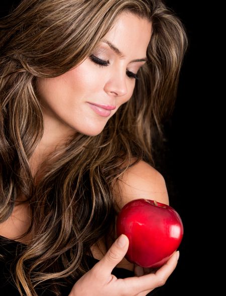 Beautiful woman holding the apple of tempation - isolated over black