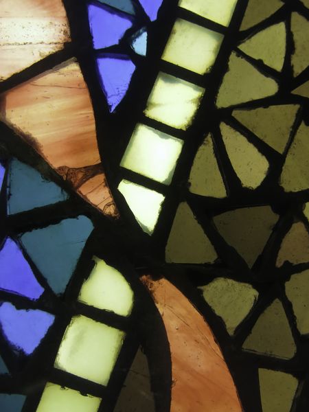 Mosaic effect in closeup of stained glass window with orange, blue, and olive green