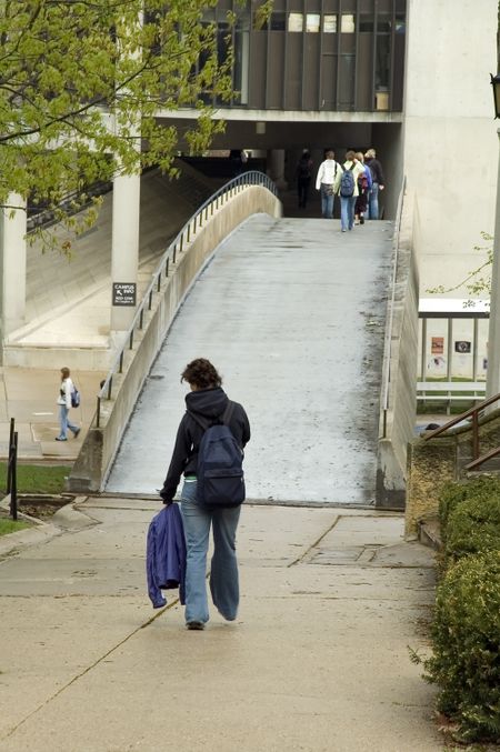 Young woman approaching footbridge on her way across college campus