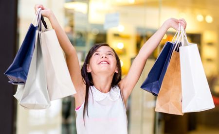 Happy girl holding shopping bags with her arms open
