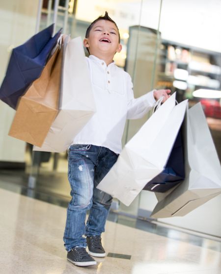 Happy shopping boy holding bags and smiling