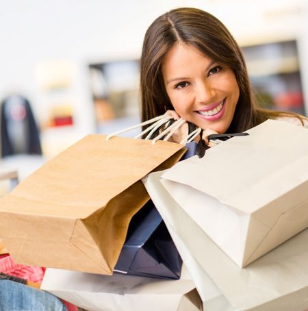 Portrait of beautiful female shopper inside a store holding shopping bags