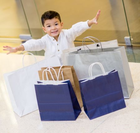 Excited boy with shopping bags looking very happy