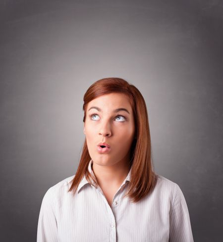 Beautiful young woman standing and thinking with copy space