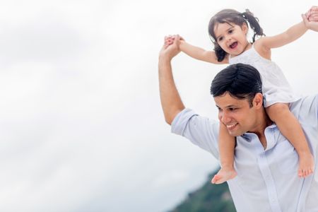 Father carrying his daughter on shoulders at the beach