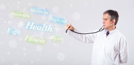 Elderly clinical doctor pointing to health and fitness collection of words