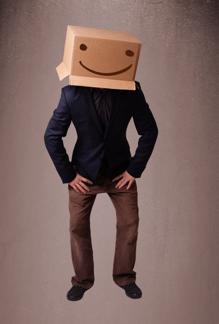 Young man standing and gesturing with a cardboard box on his head with smiley face