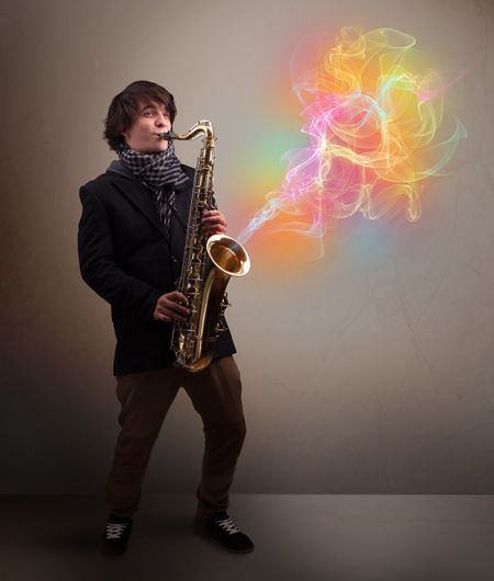 Attractive young musician playing on saxophone with colorful abstract fume comming out