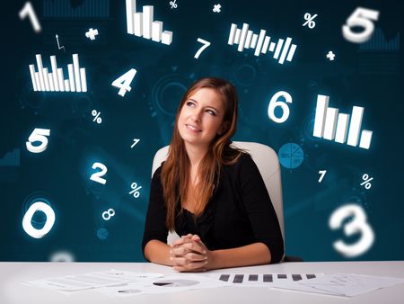 Pretty young businesswoman sitting at desk with diagrams and statistics