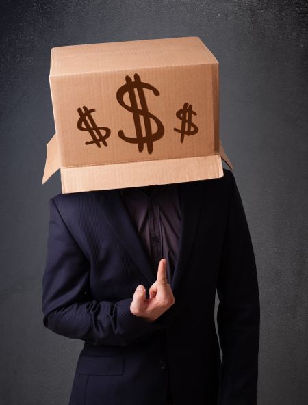 Young man standing and gesturing with a cardboard box on his head with dollar signs