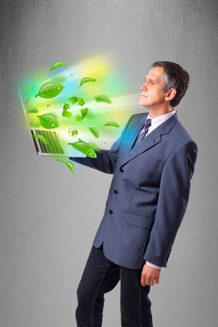 Handsome businessman holding laptop with recycle and environmental symbols