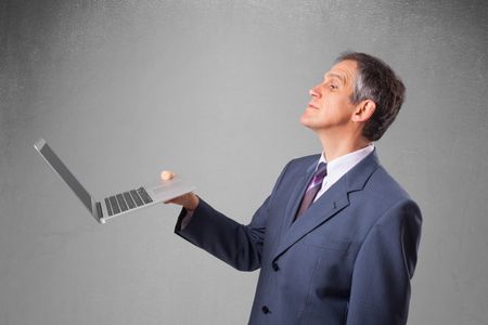 Handsome businessman in suit holding modern laptop