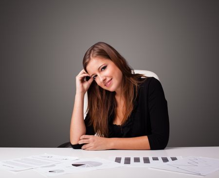 Beautiful young businesswoman sitting at desk and doing paperwork