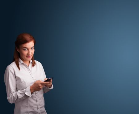 Pretty young woman standing and typing on her phone with copy space