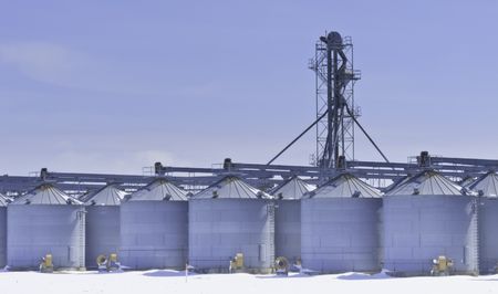 Steel grain silos and control tower above snow in March, central Illinois