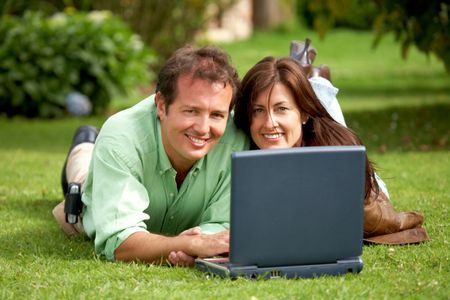 casual happy couple on a laptop computer outdoors