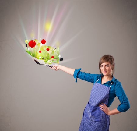 Beautiful young woman cooking fresh vegetables with abstract lights