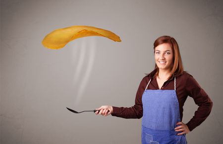 Beautiful young woman making pancakes