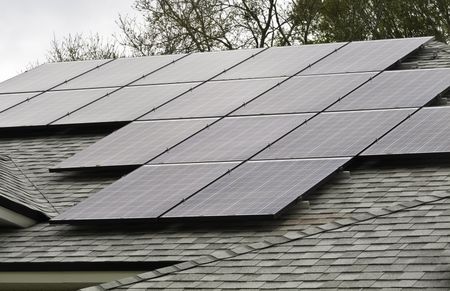 Array of solar panels on sloped roof of detached house on an overcast morning