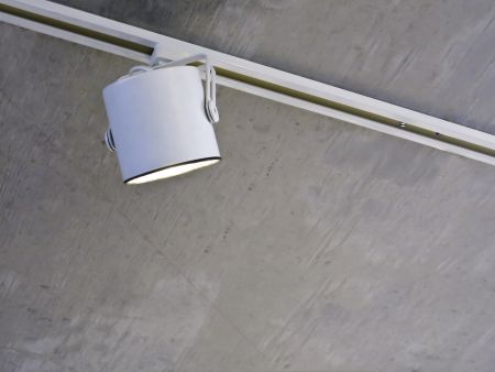 Accent light in recessed white track on stained gray ceiling above contemporary art exhibit